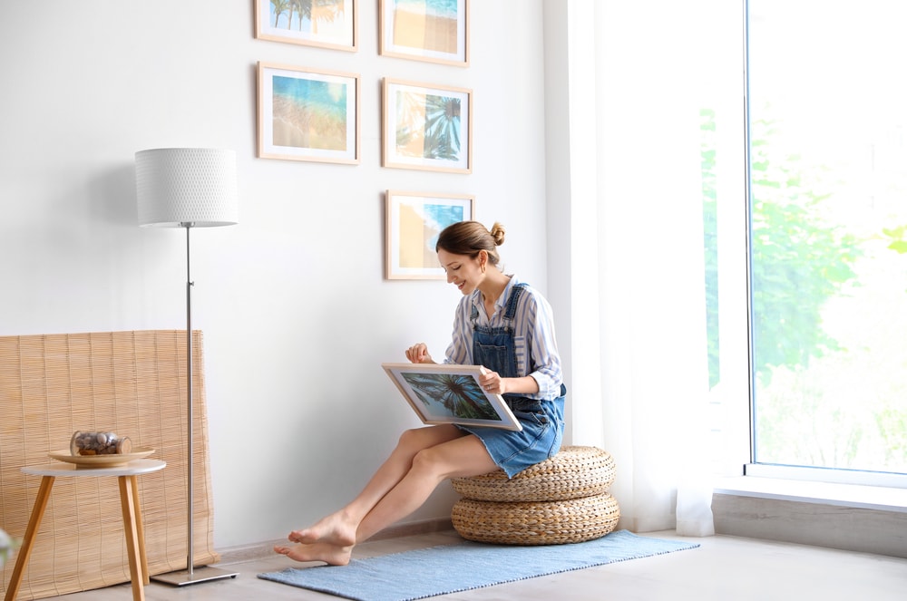 woman sitting on stool getting ready to hang artwork